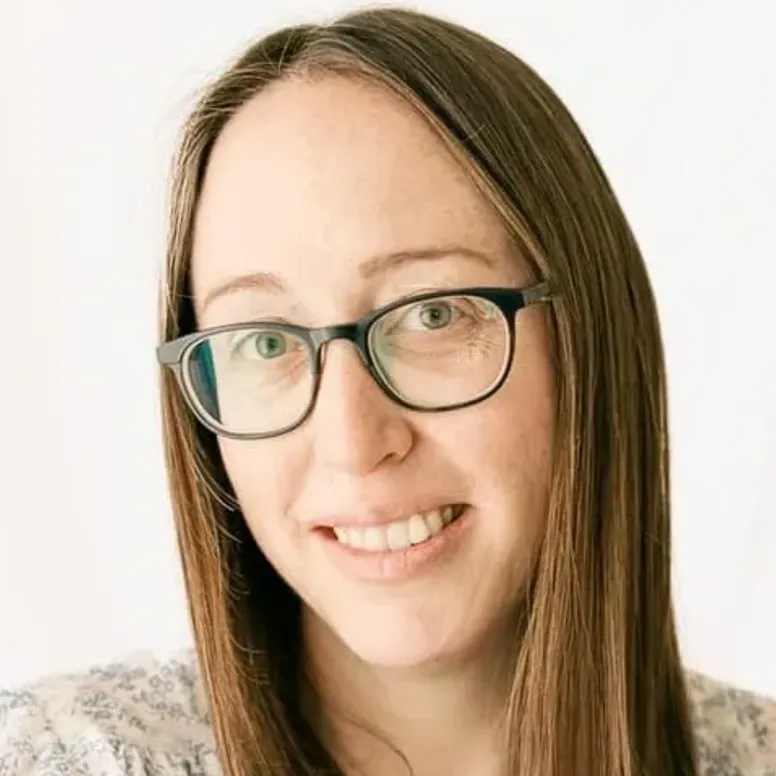 Woman with glasses smiling at camera.